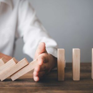 hand stopping dominoes from falling