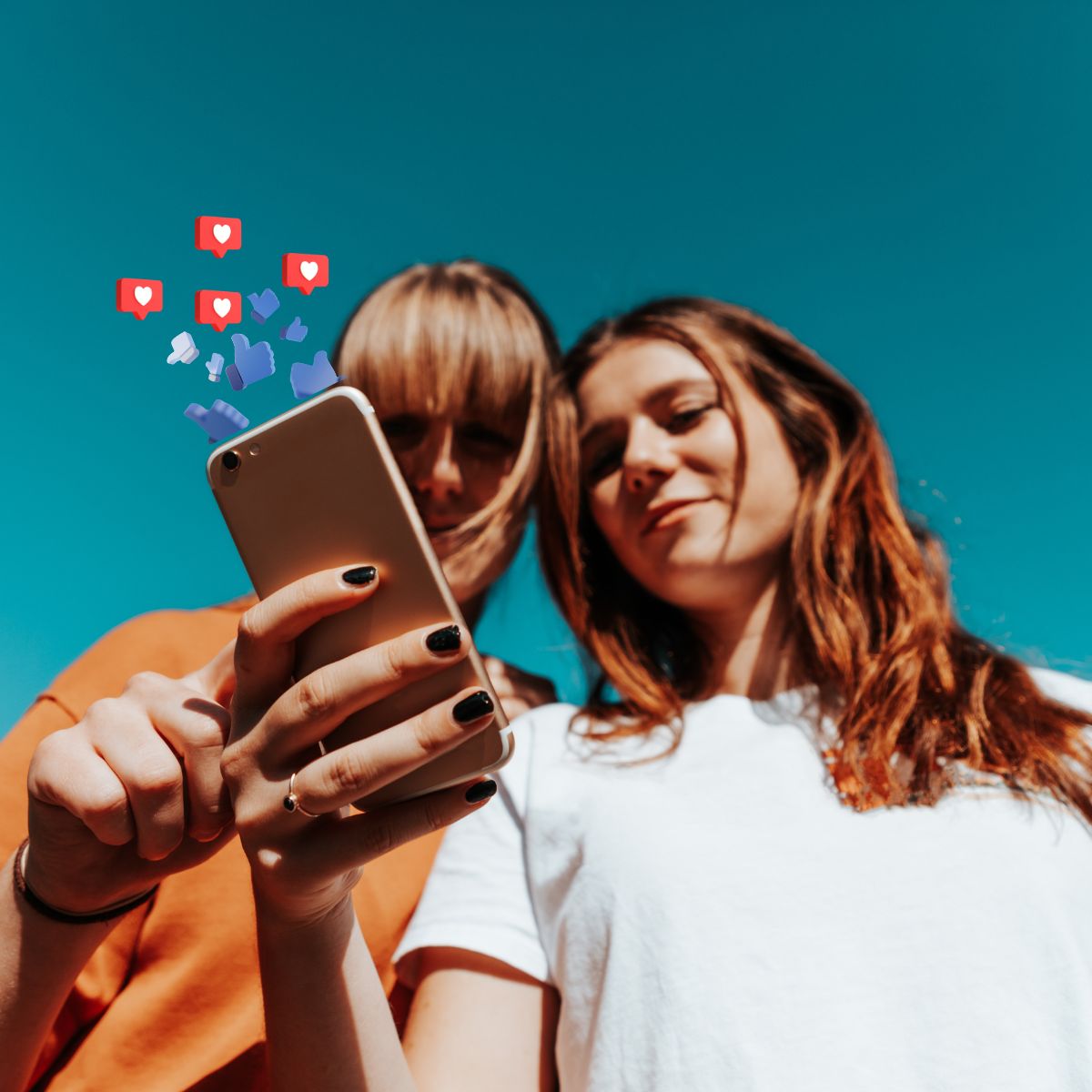 Two ladies looking at a phone with social media emojis